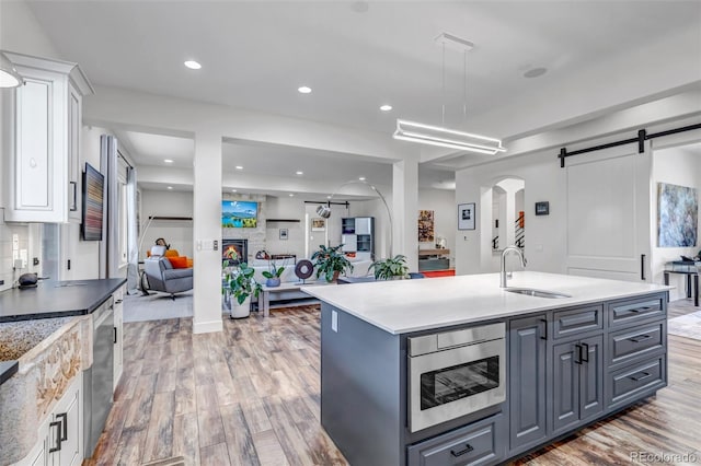 15902 W 64th Ave, Arvada, CO 80007 - kitchen featuring a sink, white cabinetry, light wood-style floors, stainless steel appliances, and a barn door
