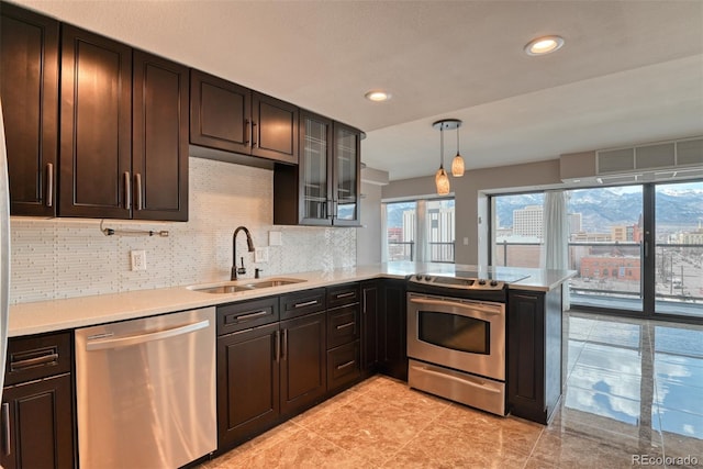 kitchen with appliances with stainless steel finishes, decorative light fixtures, sink, kitchen peninsula, and plenty of natural light