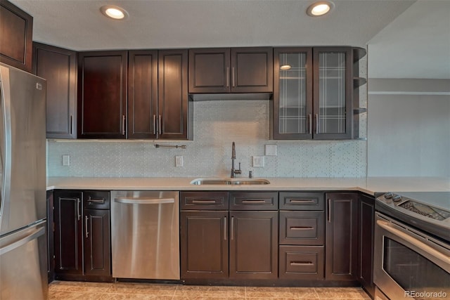 kitchen with appliances with stainless steel finishes, sink, backsplash, and dark brown cabinetry