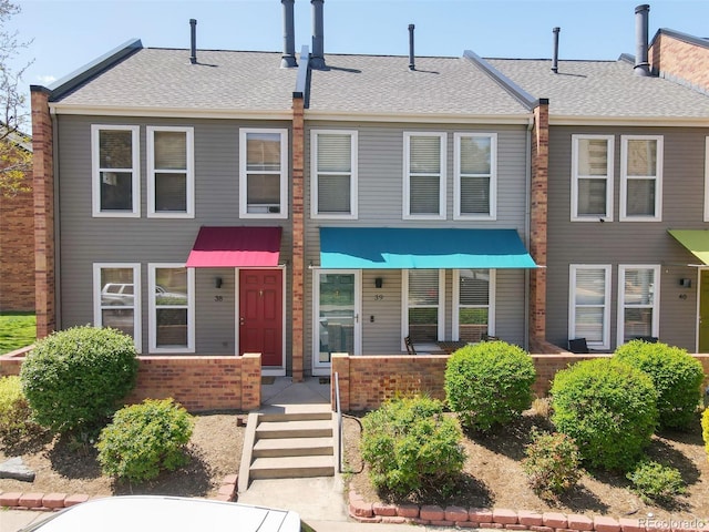 1150 Inca St Unit 39, Denver, CO 80204 - view of property featuring a shingled roof and brick siding