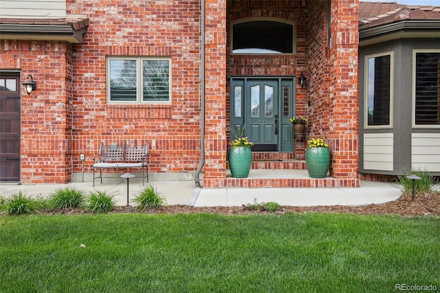 property entrance featuring a lawn and brick siding