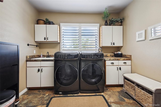 washroom with cabinet space, stone finish flooring, and washer and clothes dryer