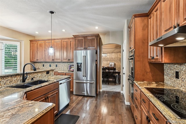 14417 W 57th Pl, Arvada, CO 80002 - kitchen featuring appliances with stainless steel finishes, a sink, arched walkways, under cabinet range hood, and light stone counters