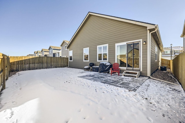 snow covered rear of property featuring central AC unit