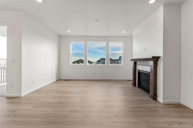 unfurnished living room with light hardwood / wood-style floors and a tile fireplace