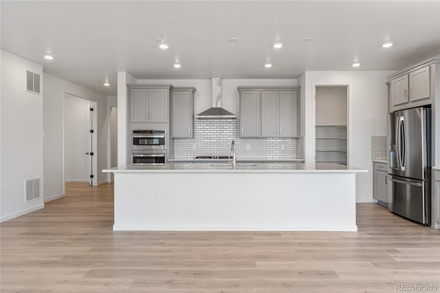 9314 Quartz St, Arvada, CO 80007 - kitchen with stainless steel appliances, gray cabinetry, wall chimney exhaust hood, an island with sink, and recessed lighting