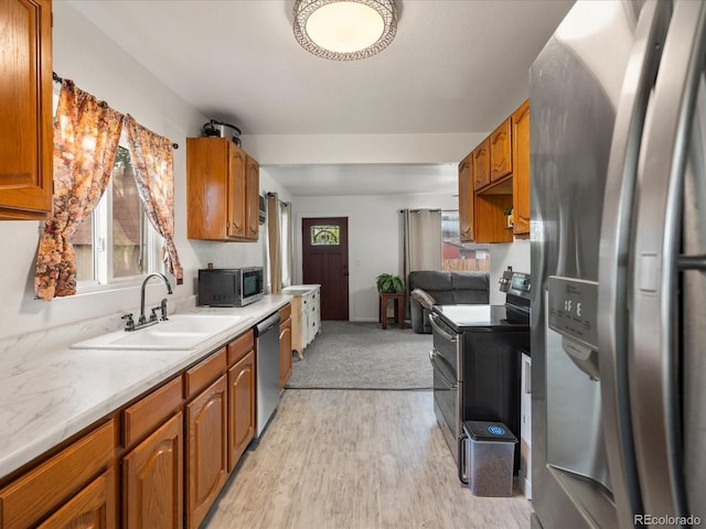 6801 W 52nd Ave, Arvada, CO 80002 - kitchen featuring appliances with stainless steel finishes, a sink, light countertops, light wood-type flooring, and brown cabinets