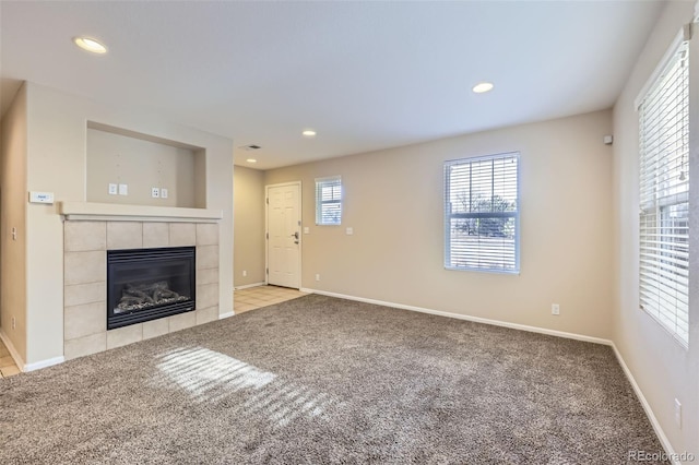 unfurnished living room featuring light colored carpet and a tiled fireplace