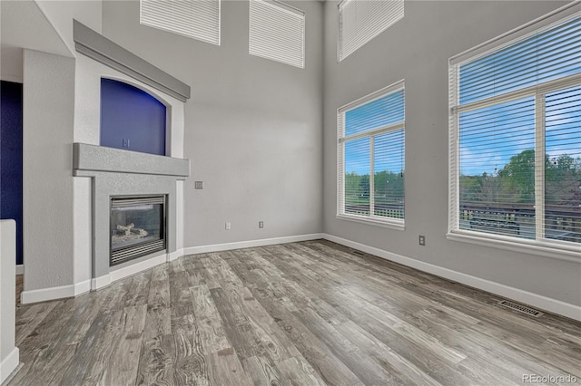 3630 Sawgrass Trl, Castle Rock, CO 80109 - unfurnished living room featuring wood finished floors, baseboards, a glass covered fireplace, and a towering ceiling