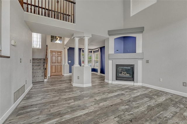 3630 Sawgrass Trl, Castle Rock, CO 80109 - unfurnished living room featuring wood finished floors, plenty of natural light, decorative columns, and a towering ceiling