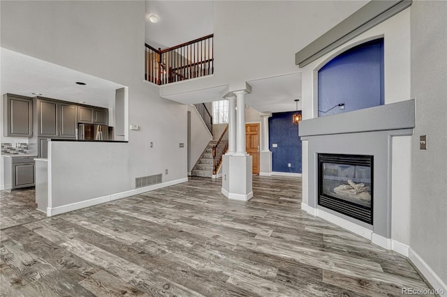 3630 Sawgrass Trl, Castle Rock, CO 80109 - unfurnished living room featuring wood finished floors, stairs, a glass covered fireplace, a high ceiling, and baseboards