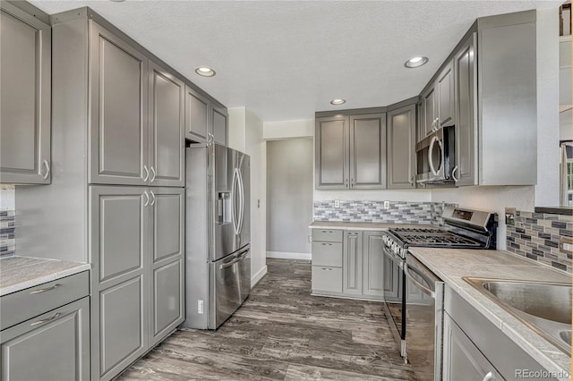 3630 Sawgrass Trl, Castle Rock, CO 80109 - kitchen with appliances with stainless steel finishes, gray cabinets, dark wood finished floors, recessed lighting, and light countertops