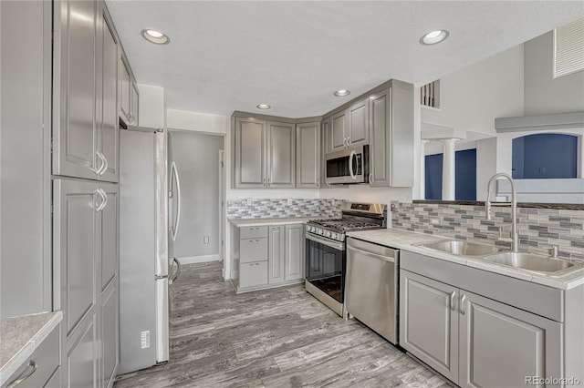 3630 Sawgrass Trl, Castle Rock, CO 80109 - kitchen featuring stainless steel appliances, gray cabinetry, a sink, light wood-type flooring, and light countertops