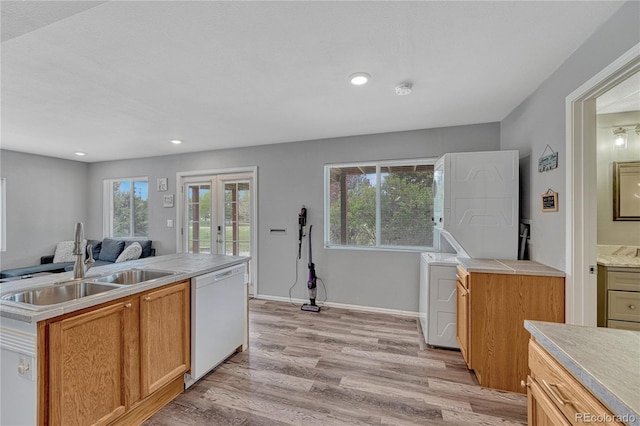 3630 Sawgrass Trl, Castle Rock, CO 80109 - kitchen with white dishwasher, stacked washer / drying machine, a sink, light wood finished floors, and recessed lighting