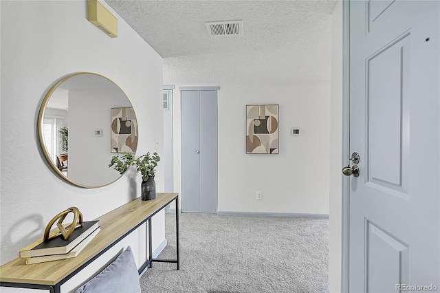 hallway with a textured ceiling and light colored carpet