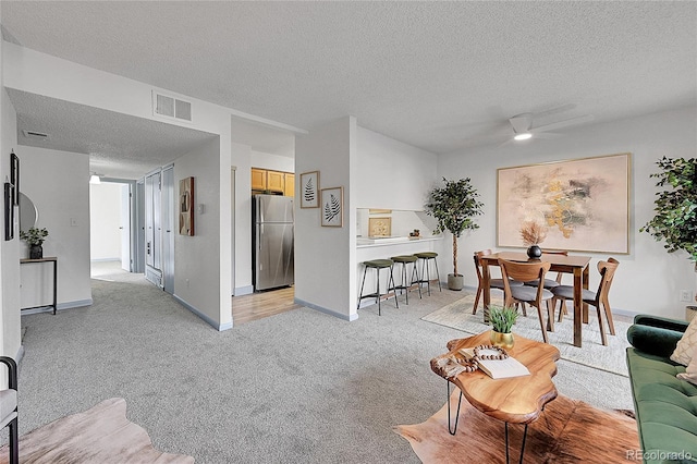 carpeted living room featuring ceiling fan and a textured ceiling