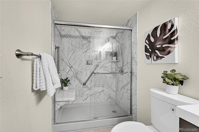 bathroom with an enclosed shower, vanity, toilet, and a textured ceiling