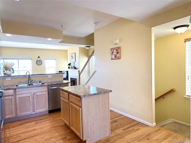 kitchen with a kitchen island, sink, stainless steel dishwasher, and light hardwood / wood-style floors