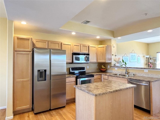 kitchen with a kitchen island, appliances with stainless steel finishes, light brown cabinetry, sink, and light hardwood / wood-style flooring