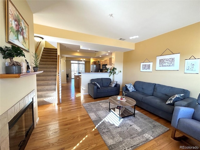 living room featuring a tile fireplace and light hardwood / wood-style flooring