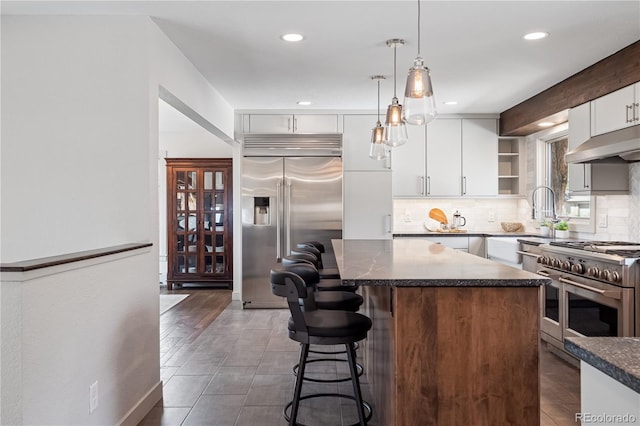 31607 Broadmoor Dr, Evergreen, CO 80439 - kitchen with high quality appliances, under cabinet range hood, dark countertops, open shelves, and backsplash