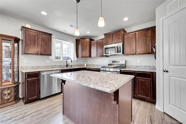 10684 Calista Way, Fountain, CO 80817 - kitchen featuring stainless steel appliances, light wood-style floors, a center island, dark brown cabinets, and light stone counters