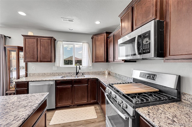 10684 Calista Way, Fountain, CO 80817 - kitchen featuring stainless steel appliances, light stone countertops, recessed lighting, light wood-style floors, and dark brown cabinets