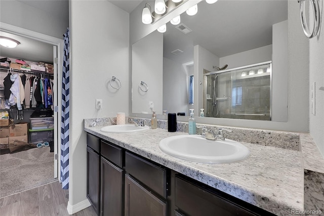 10684 Calista Way, Fountain, CO 80817 - full bathroom with a stall shower, double vanity, wood finished floors, and a spacious closet