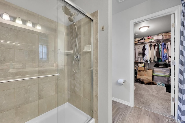 10684 Calista Way, Fountain, CO 80817 - bathroom with a stall shower, a spacious closet, and wood finished floors
