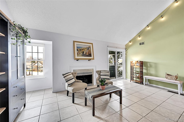 sitting room featuring light tile patterned floors, a textured ceiling, vaulted ceiling, and a wealth of natural light