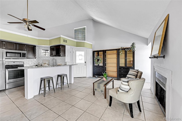 tiled living room with ceiling fan, a fireplace, a textured ceiling, heating unit, and lofted ceiling