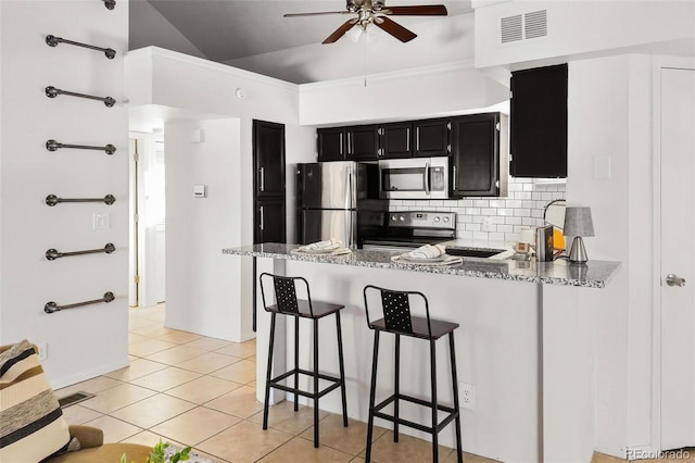 kitchen with tasteful backsplash, visible vents, lofted ceiling, appliances with stainless steel finishes, and dark cabinets