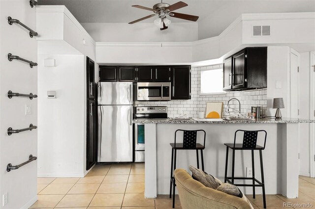 kitchen featuring stainless steel appliances, visible vents, dark cabinets, and light tile patterned floors