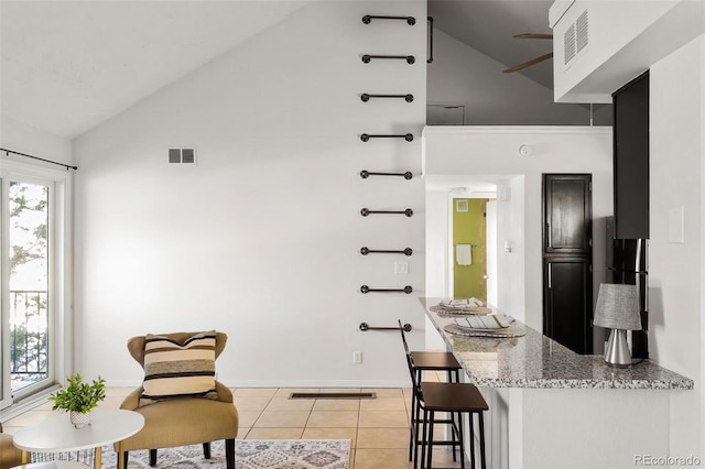 interior space featuring high vaulted ceiling, light stone countertops, visible vents, and light tile patterned floors