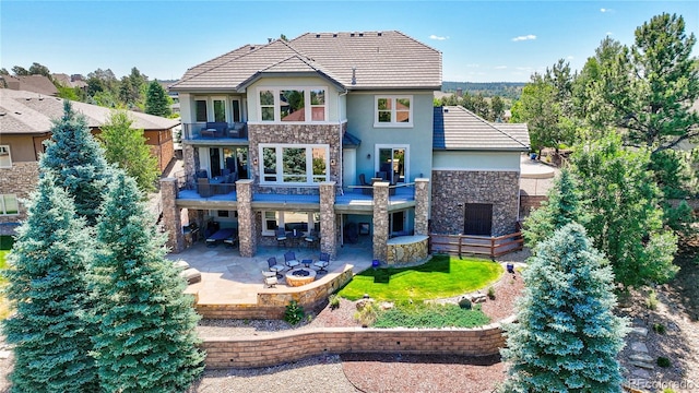 rear view of property with a lawn, a balcony, and a patio