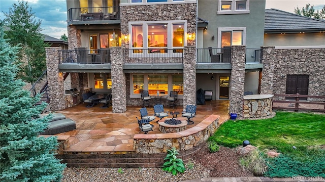 rear view of property with a fire pit, a patio area, a balcony, and a yard