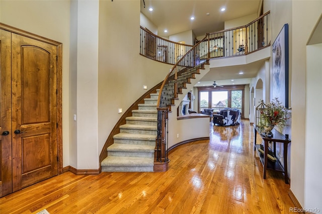 foyer entrance with ceiling fan, a high ceiling, and light wood-type flooring