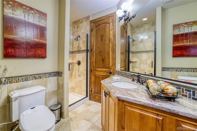 bathroom featuring vanity, a shower with shower door, tile walls, and toilet