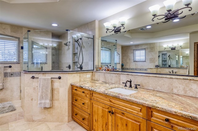 bathroom featuring vanity, a tile shower, a wealth of natural light, and a chandelier