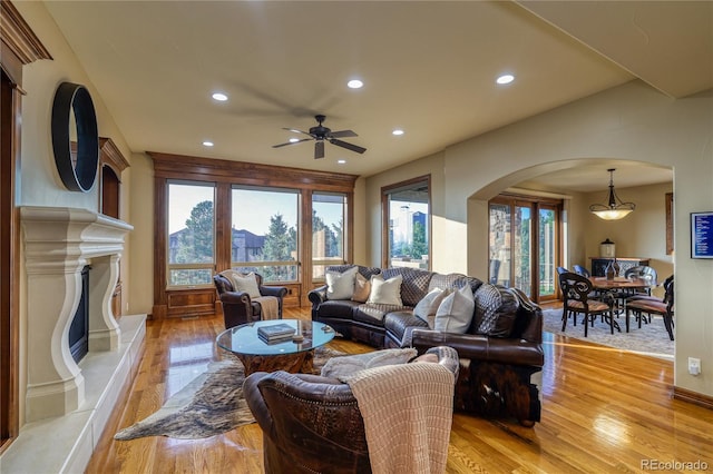 living room featuring ceiling fan, a premium fireplace, and light hardwood / wood-style flooring