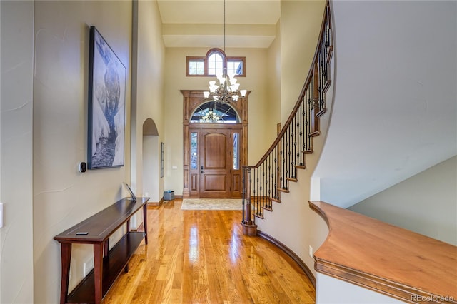 entrance foyer featuring a towering ceiling, a chandelier, and light wood-type flooring