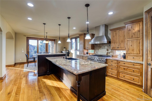 kitchen featuring decorative backsplash, a spacious island, wall chimney exhaust hood, and sink