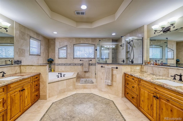 bathroom featuring plus walk in shower, vanity, a raised ceiling, and tile walls