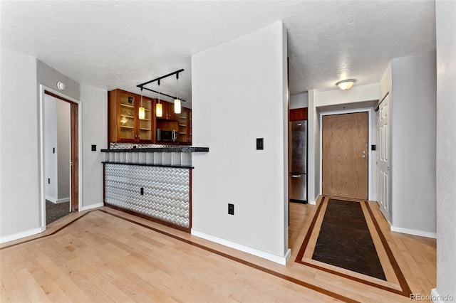 foyer with a textured ceiling, light hardwood / wood-style floors, and track lighting