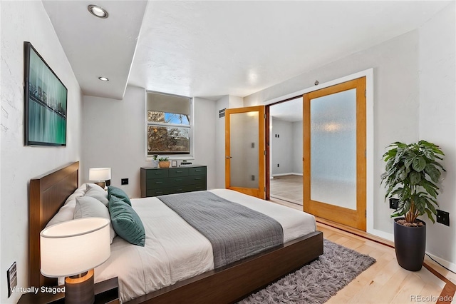 bedroom with french doors and light hardwood / wood-style floors