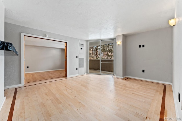 spare room with a textured ceiling and light wood-type flooring