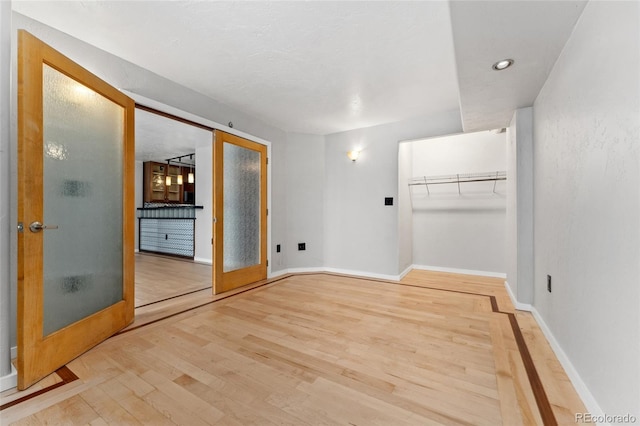 unfurnished bedroom with light hardwood / wood-style floors, a closet, and french doors