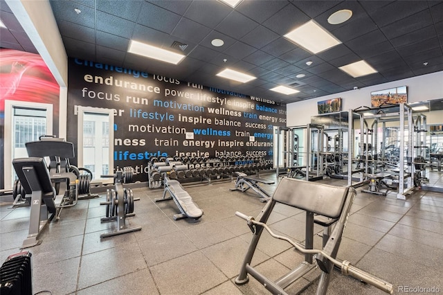 exercise room with a towering ceiling, a drop ceiling, and visible vents