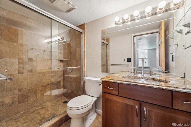 bathroom featuring vanity, a shower stall, toilet, and visible vents