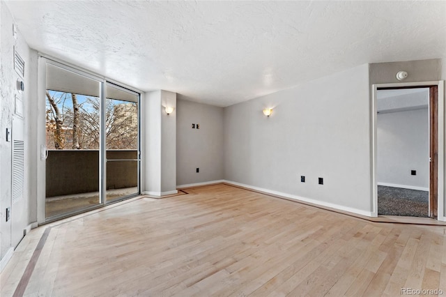 unfurnished living room featuring baseboards, expansive windows, a textured ceiling, and wood finished floors